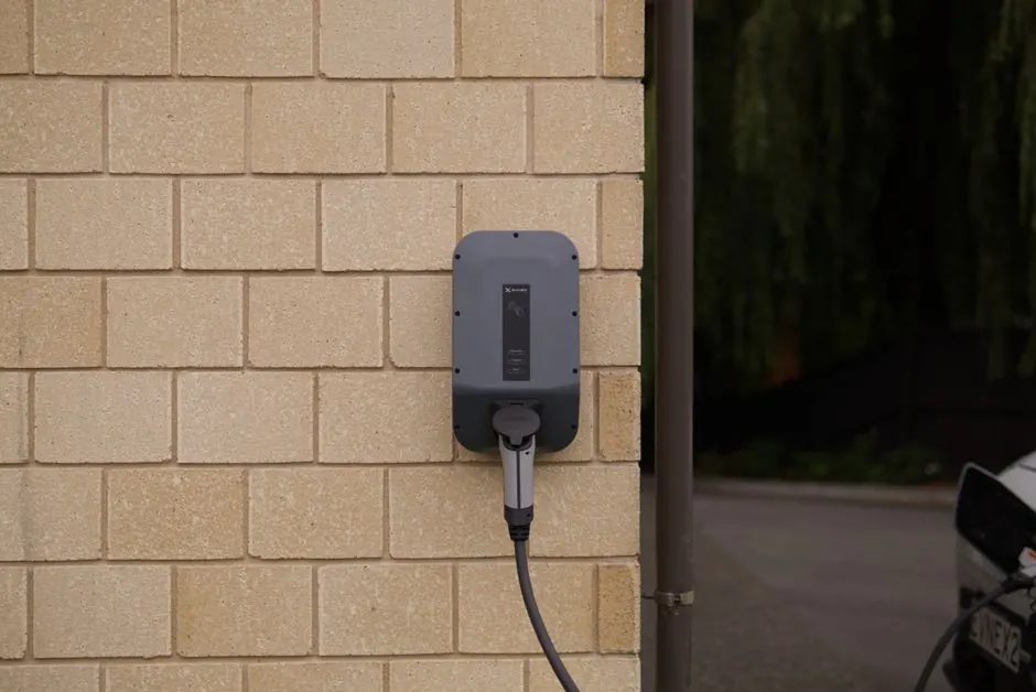 A wall-mounted electric vehicle charging station installed on a brick wall in Christchurch, New Zealand.